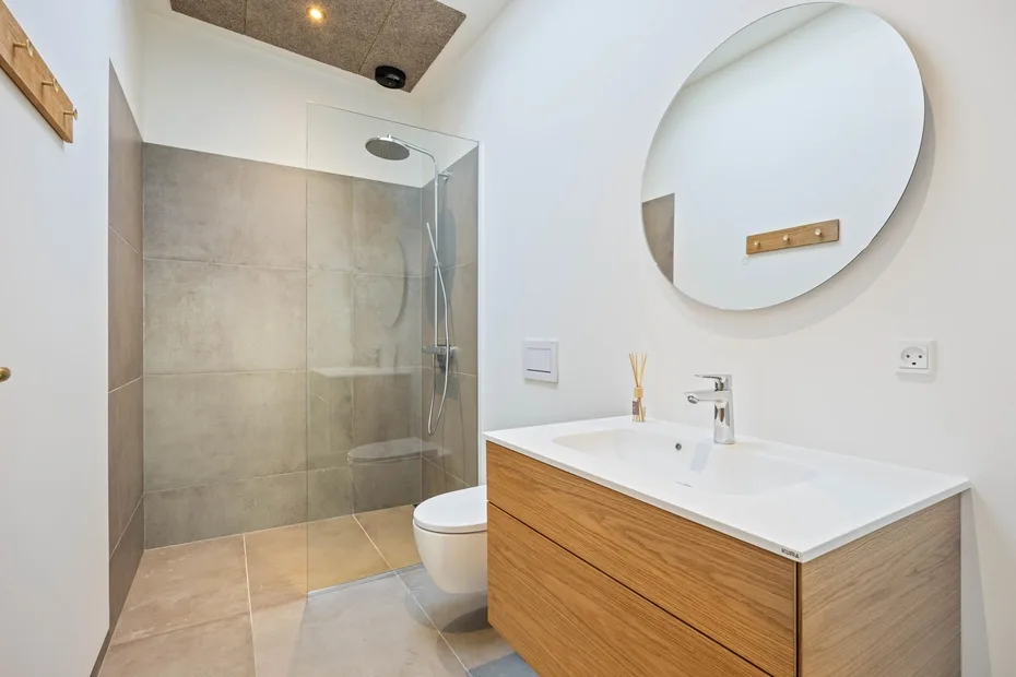 Un baño moderno con ducha de vidrio y un lavabo con frente de madera.
