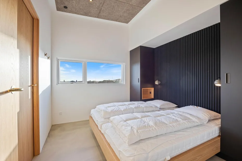 Un dormitorio con dos camas y ventanas con vistas al exterior.