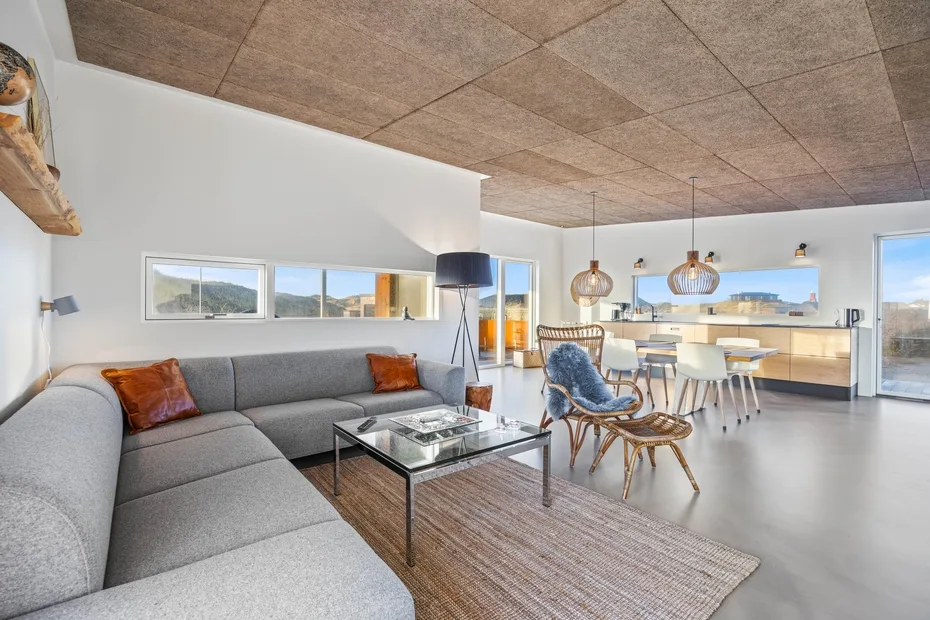 Una sala de estar y comedor de concepto abierto con un sofá seccional y ventanales.