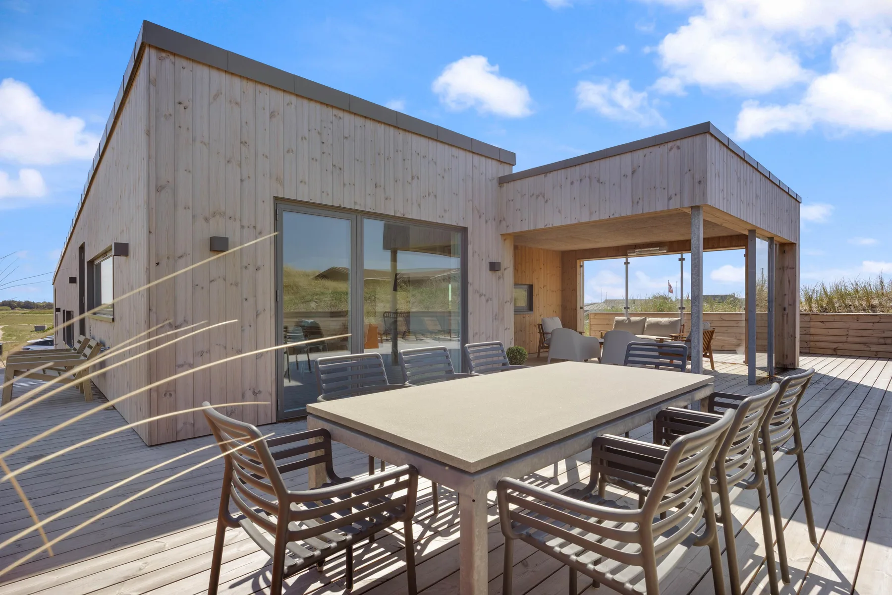 Una terraza exterior con mesa de comedor y asientos junto a un edificio moderno.