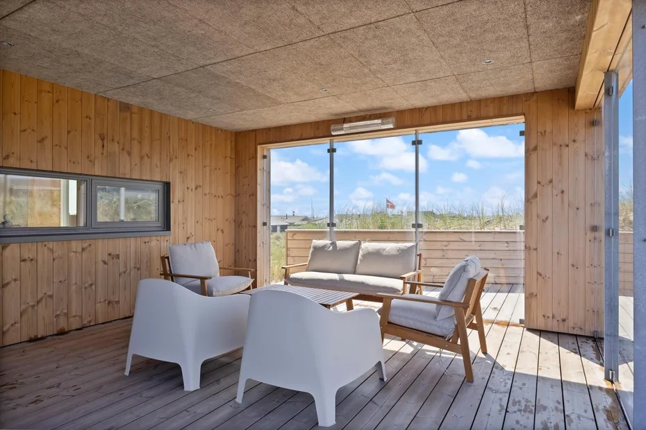 Un solárium revestido de madera, con asientos y grandes ventanas hacia el paisaje.