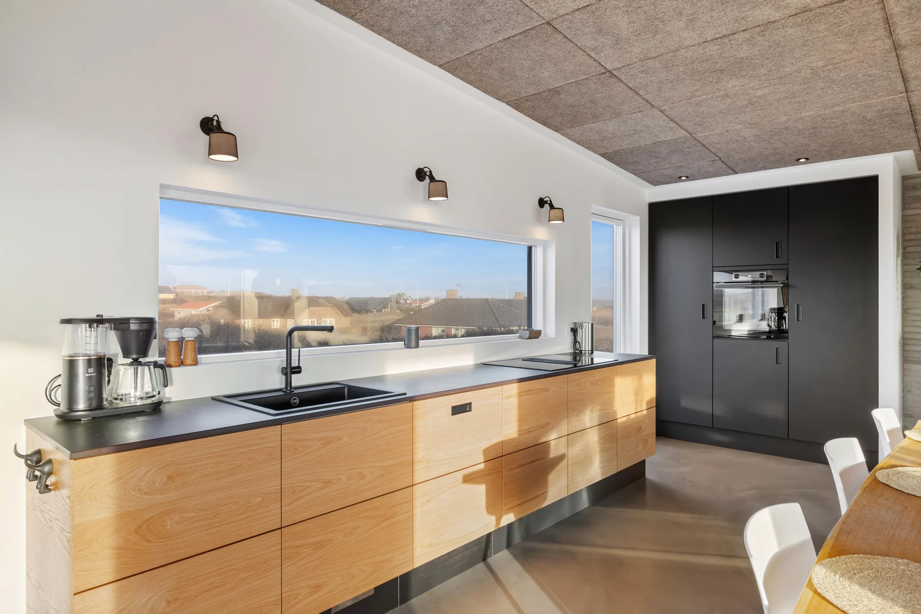 Una cocina moderna con gabinetes de madera, una ventana amplia y electrodomésticos integrados.