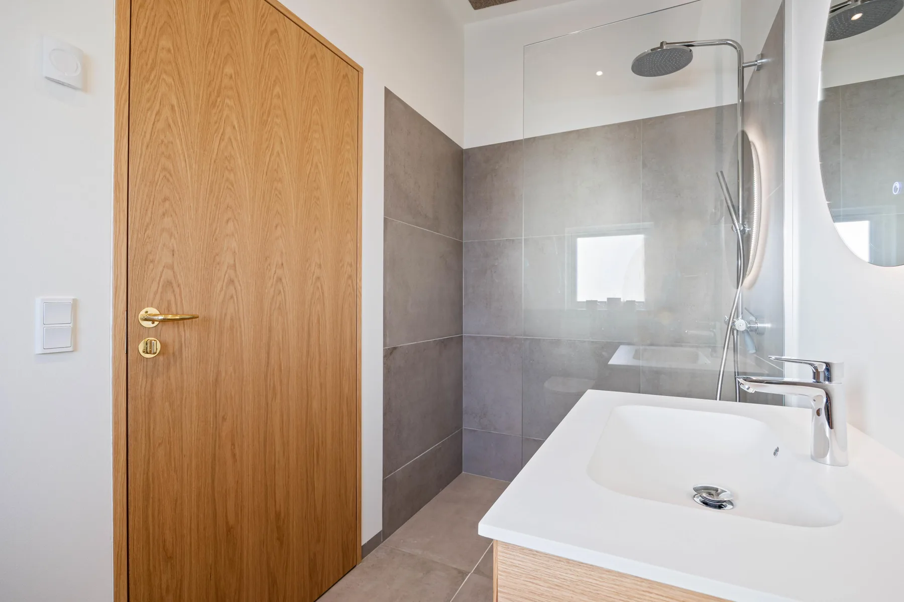 Un baño moderno con ducha a ras de suelo y lavabo blanco.