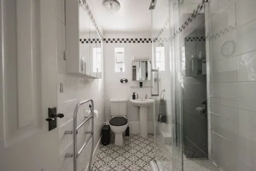 Un baño alicatado con lavabo, inodoro y ducha de cristal.
