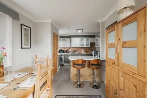 Un comedor se abre a una cocina, con una barra y asientos.