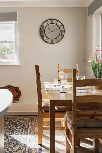 Comedor con una mesa de madera puesta junto a una ventana luminosa.