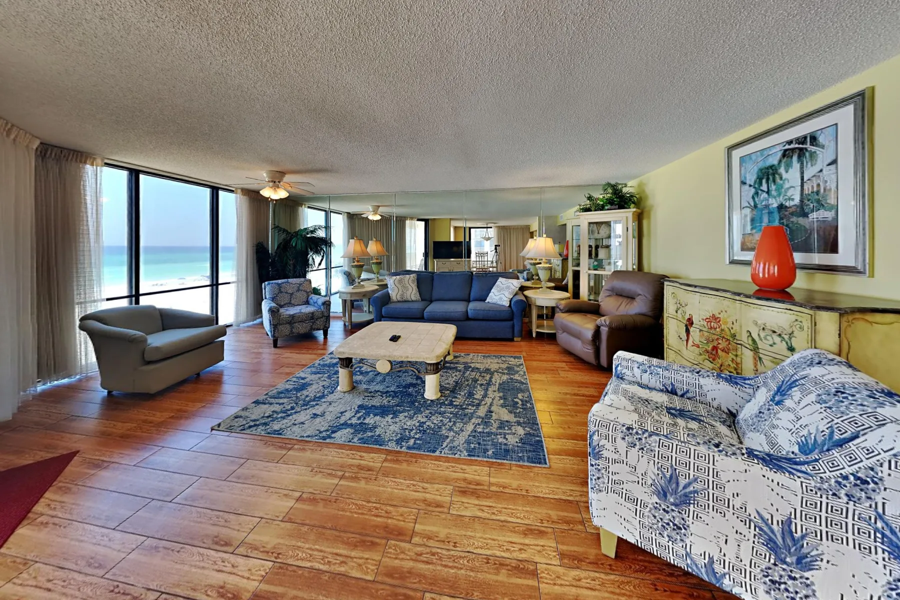 A living room with seating arranged around a coffee table beside large windows.