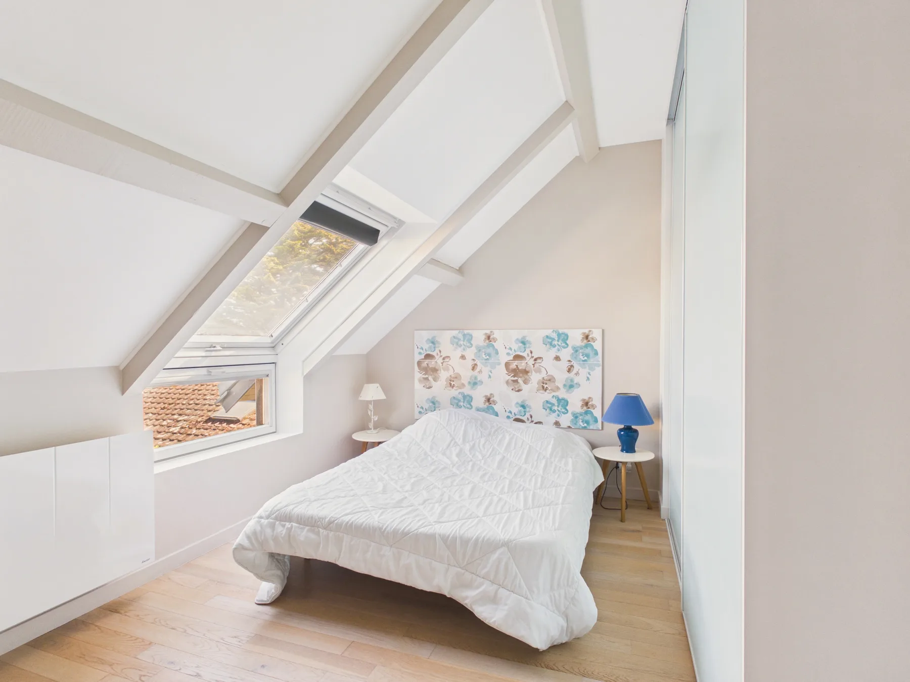 Un dormitorio luminoso con una cama bajo tragaluces inclinados.