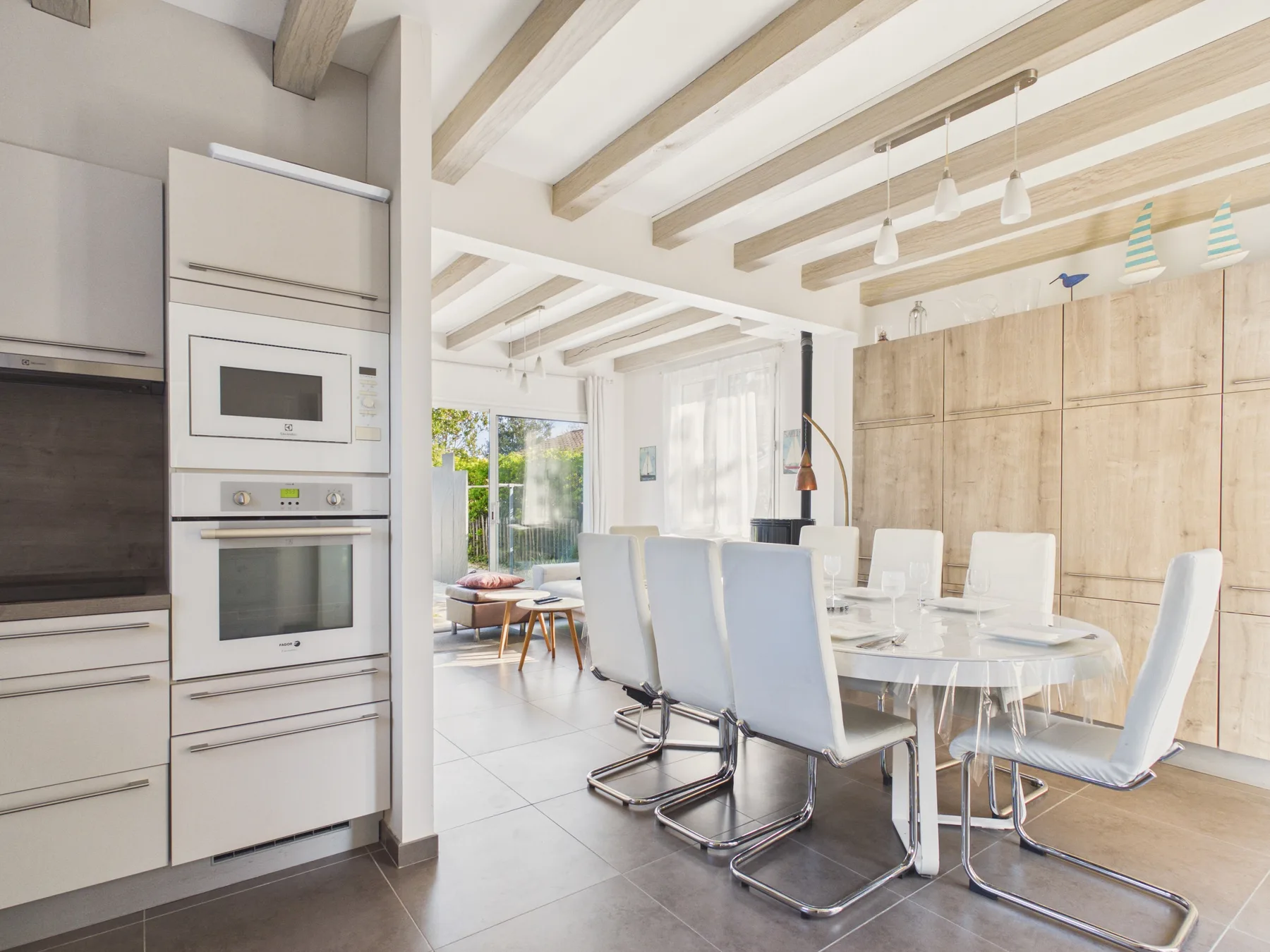 Un comedor luminoso con una mesa, asientos y una cocina integrada.