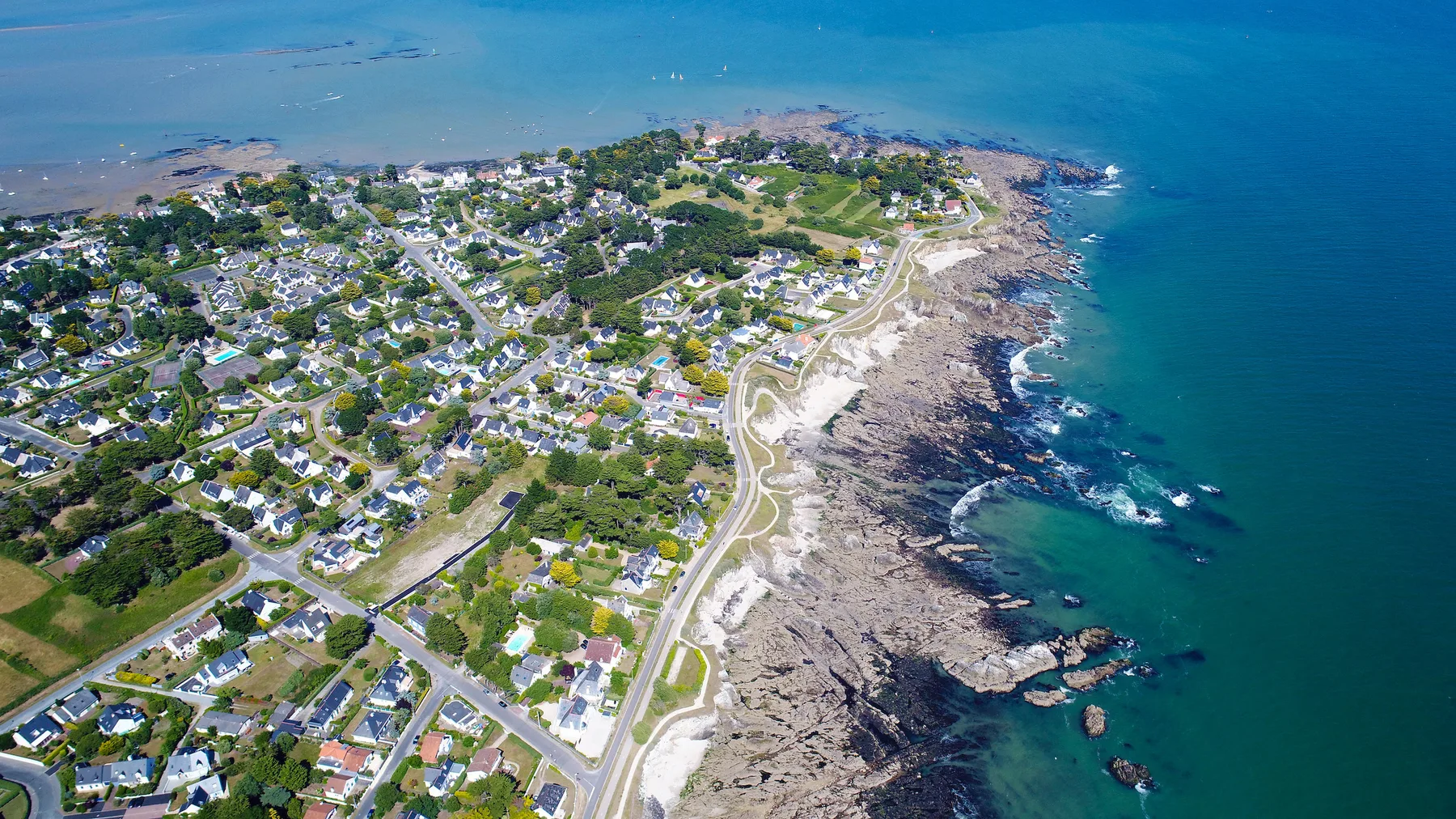 Un barrio costero junto a una costa rocosa y aguas azules.