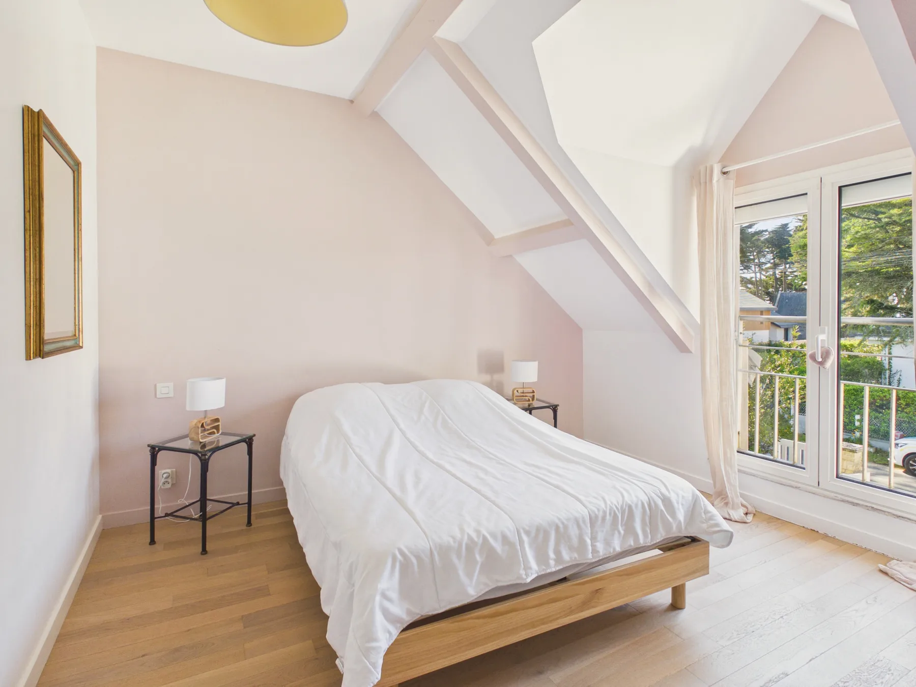Un dormitorio con una cama bajo un techo inclinado y junto a puertas de vidrio.