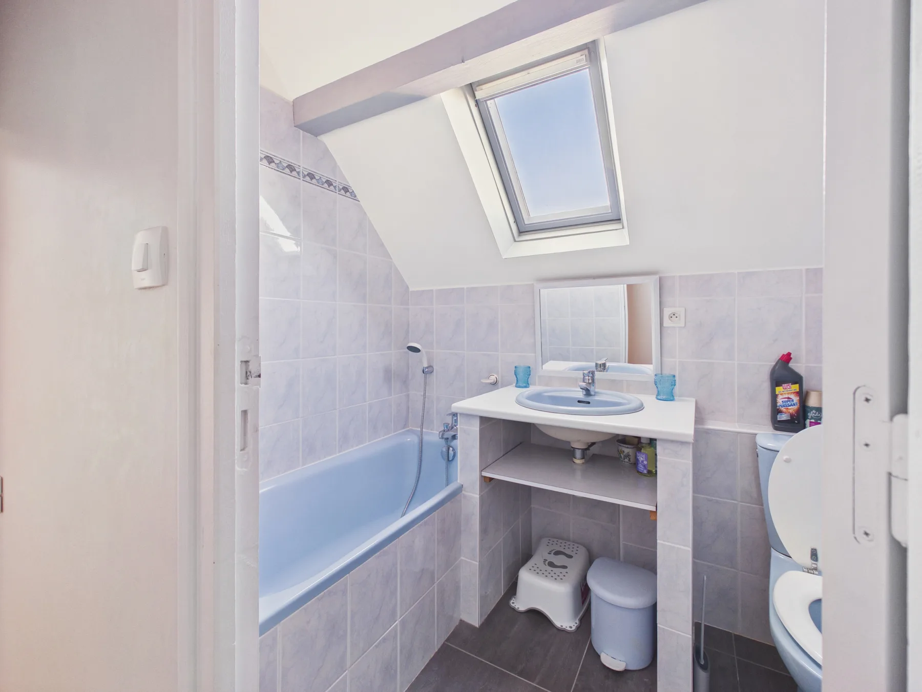 Un baño alicatado con bañera, lavabo y tragaluz.