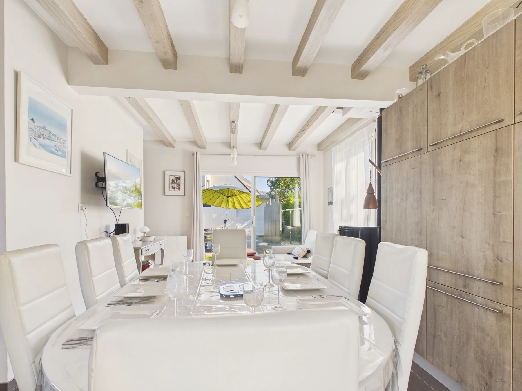 Un comedor luminoso con una mesa larga y asientos blancos.