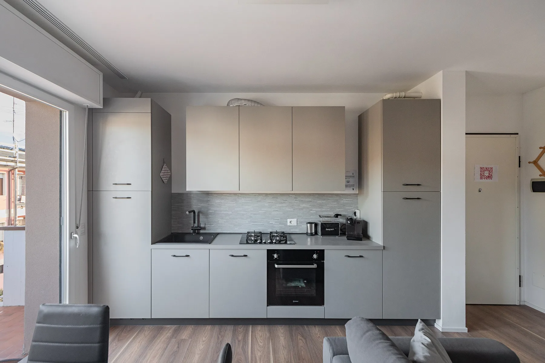 A modern kitchen with light cabinets, a dark countertop, and a built-in oven.