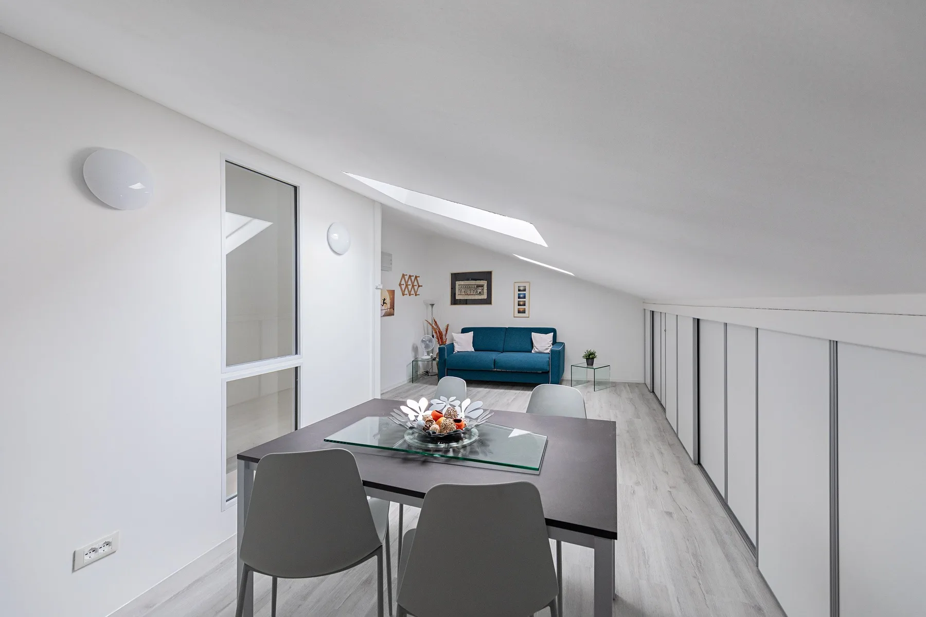 A bright dining area with a table and chairs beside a small seating area.