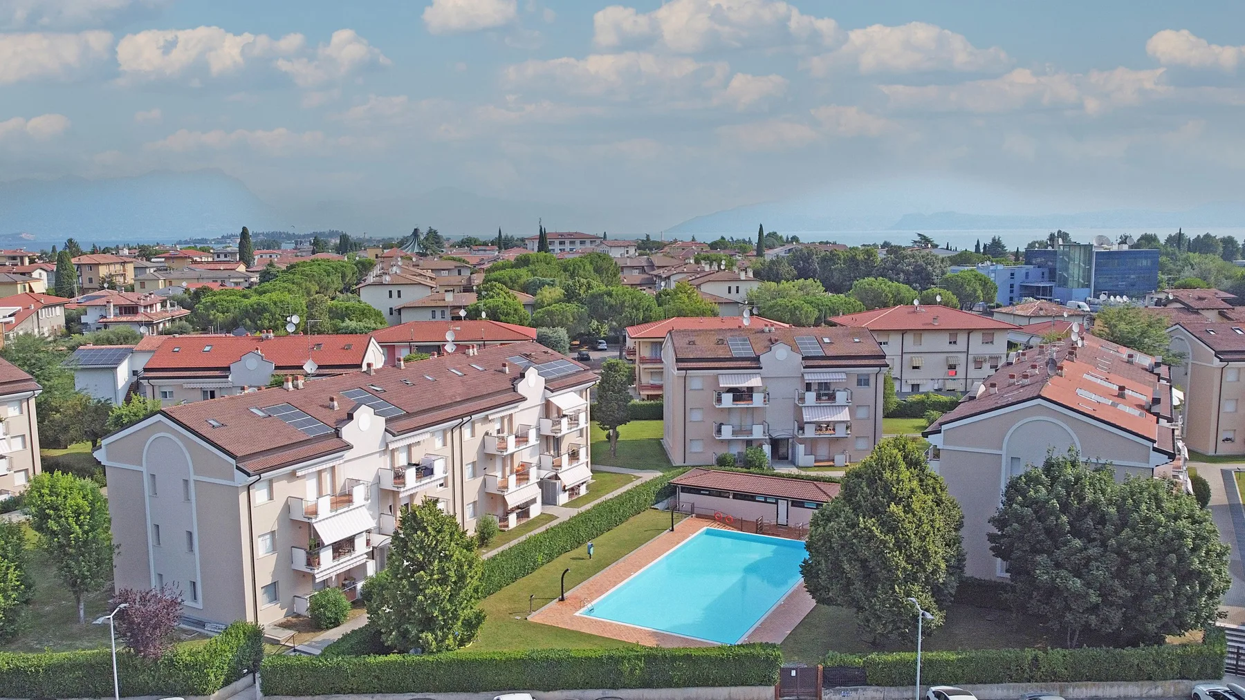 Aerial view of a residential neighborhood with a swimming pool and distant hills.