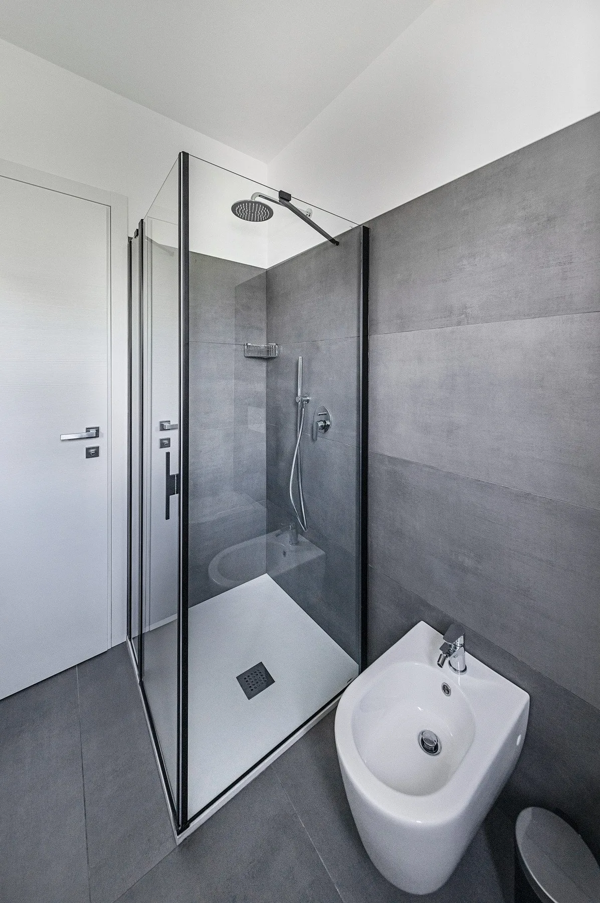A modern bathroom with a glass-enclosed shower and a bidet.