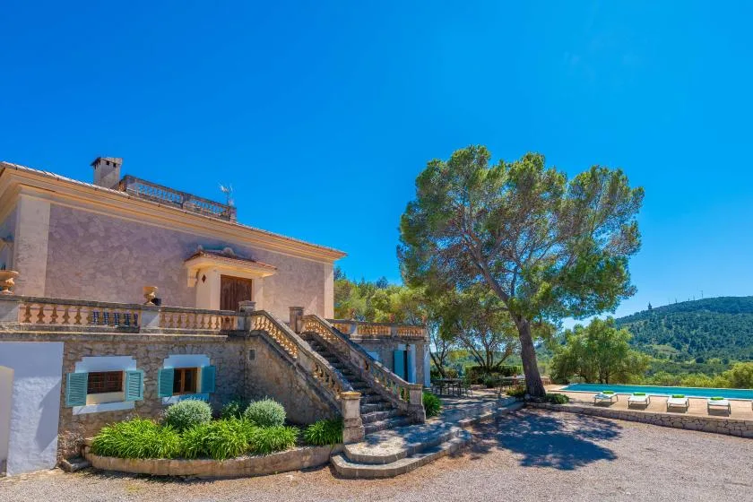 Una casa de piedra y una terraza exterior junto a un árbol grande.