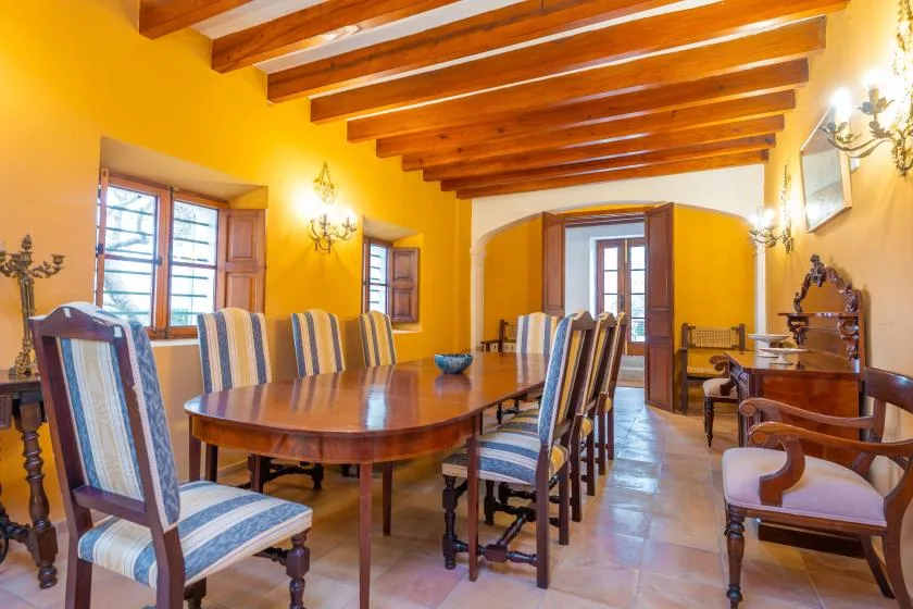 Un comedor con una mesa larga y asientos tapizados a rayas.