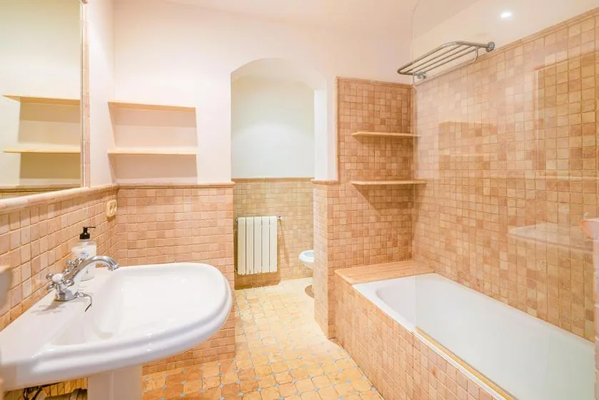 Un baño revestido de azulejos con bañera, lavabo y radiador de pared.