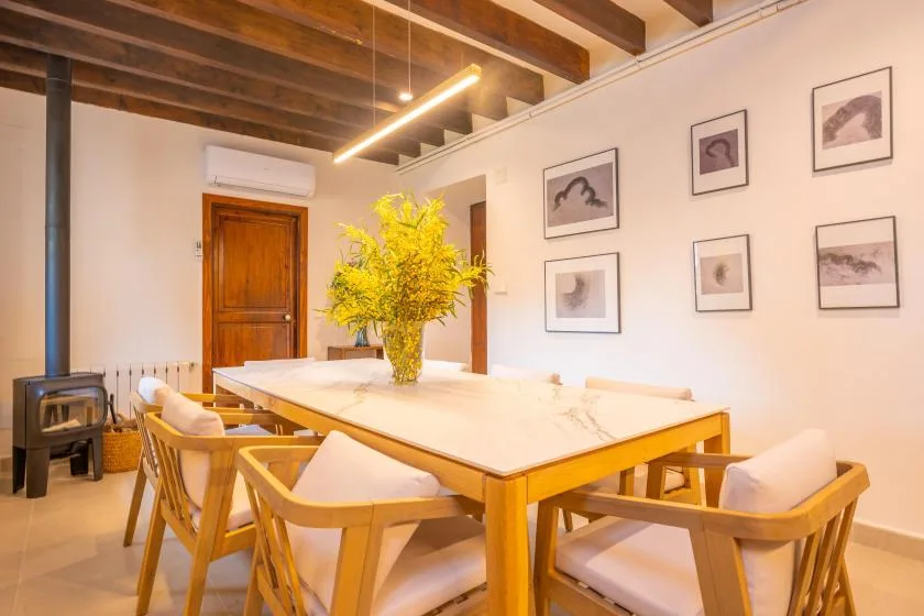 Comedor con una mesa larga de madera, asientos acolchados y cuadros enmarcados.