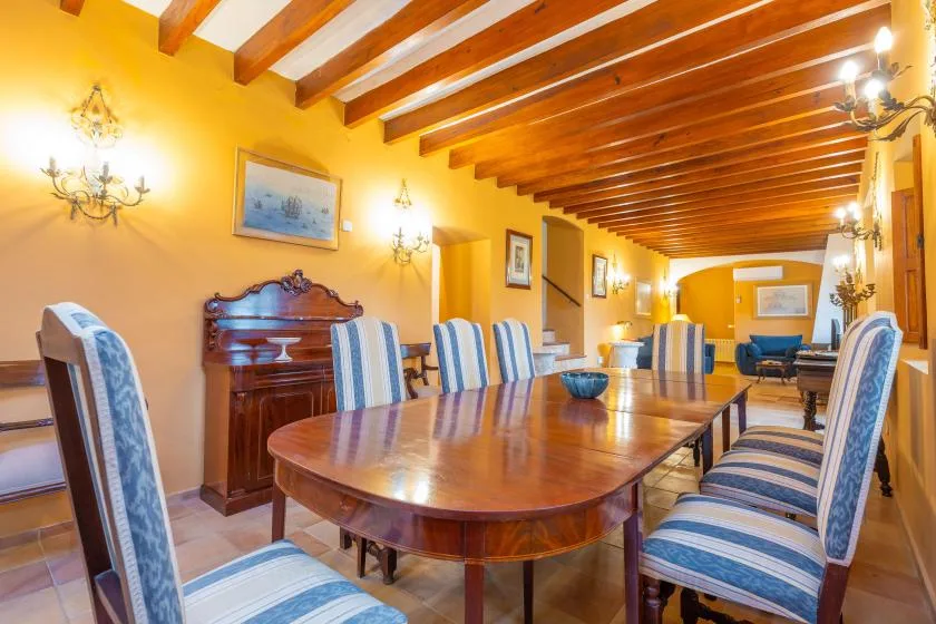 Un comedor con una mesa larga de madera y asientos tapizados a rayas.
