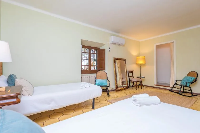 Dormitorio con dos camas, una ventana y una pequeña zona de estar.