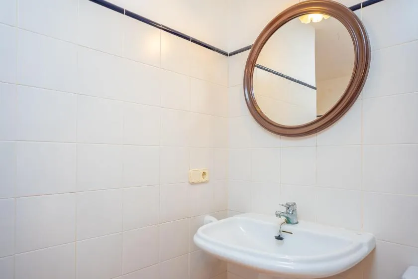 Un lavabo de baño está bajo un espejo redondo.