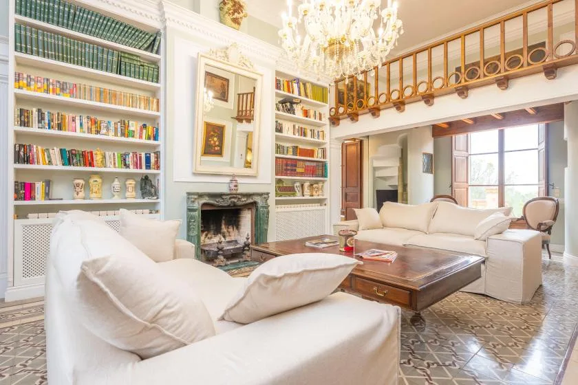 Una sala luminosa con estanterías empotradas, una chimenea y asientos alrededor de una mesa de centro.