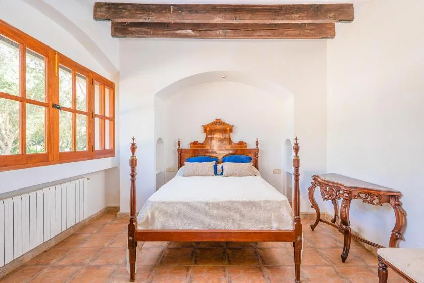 Un dormitorio con una cama de madera bajo vigas de techo expuestas.