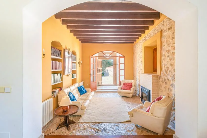 Una sala de estar en tonos cálidos con asientos, chimenea y vigas vistas en el techo.