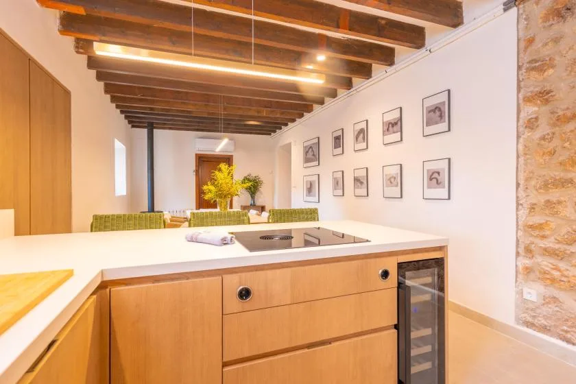 Una cocina luminosa con isla blanca, armarios de madera y vigas de techo vistas.