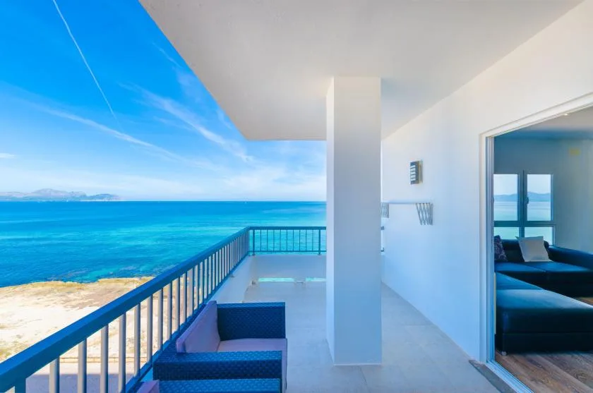A seaside balcony with blue seating overlooks the ocean.