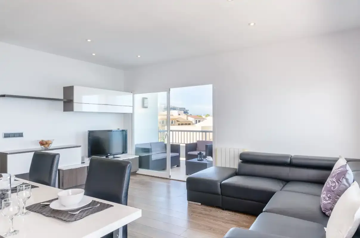 Un salón luminoso con asientos y una mesa de comedor junto a puertas de cristal.