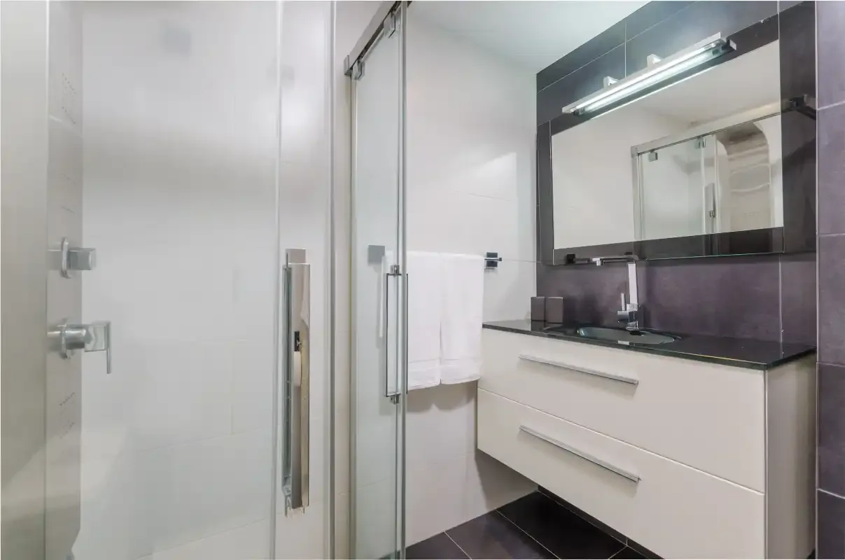 Un baño moderno con una ducha de vidrio y un tocador.