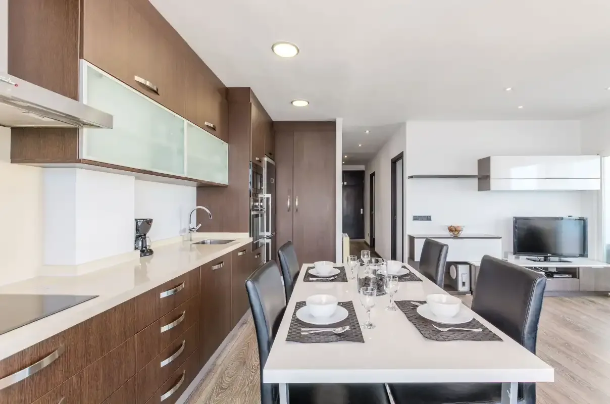 Cocina moderna y comedor con una mesa larga y una sala de estar abierta.