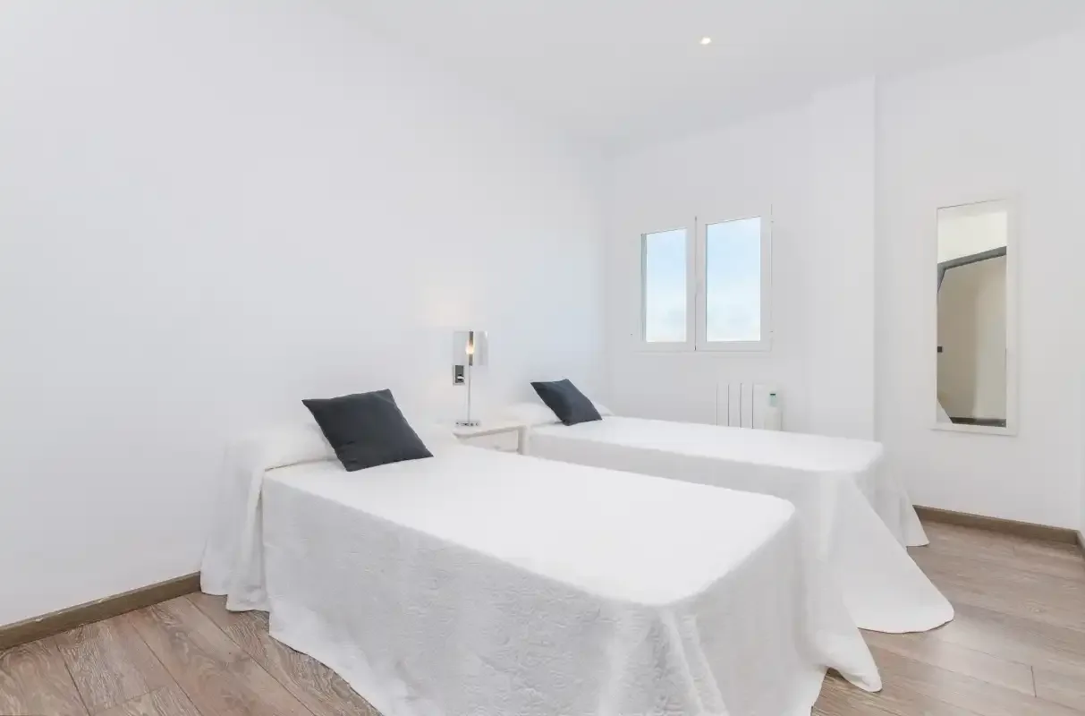 Un dormitorio luminoso con dos camas individuales y ventanas.