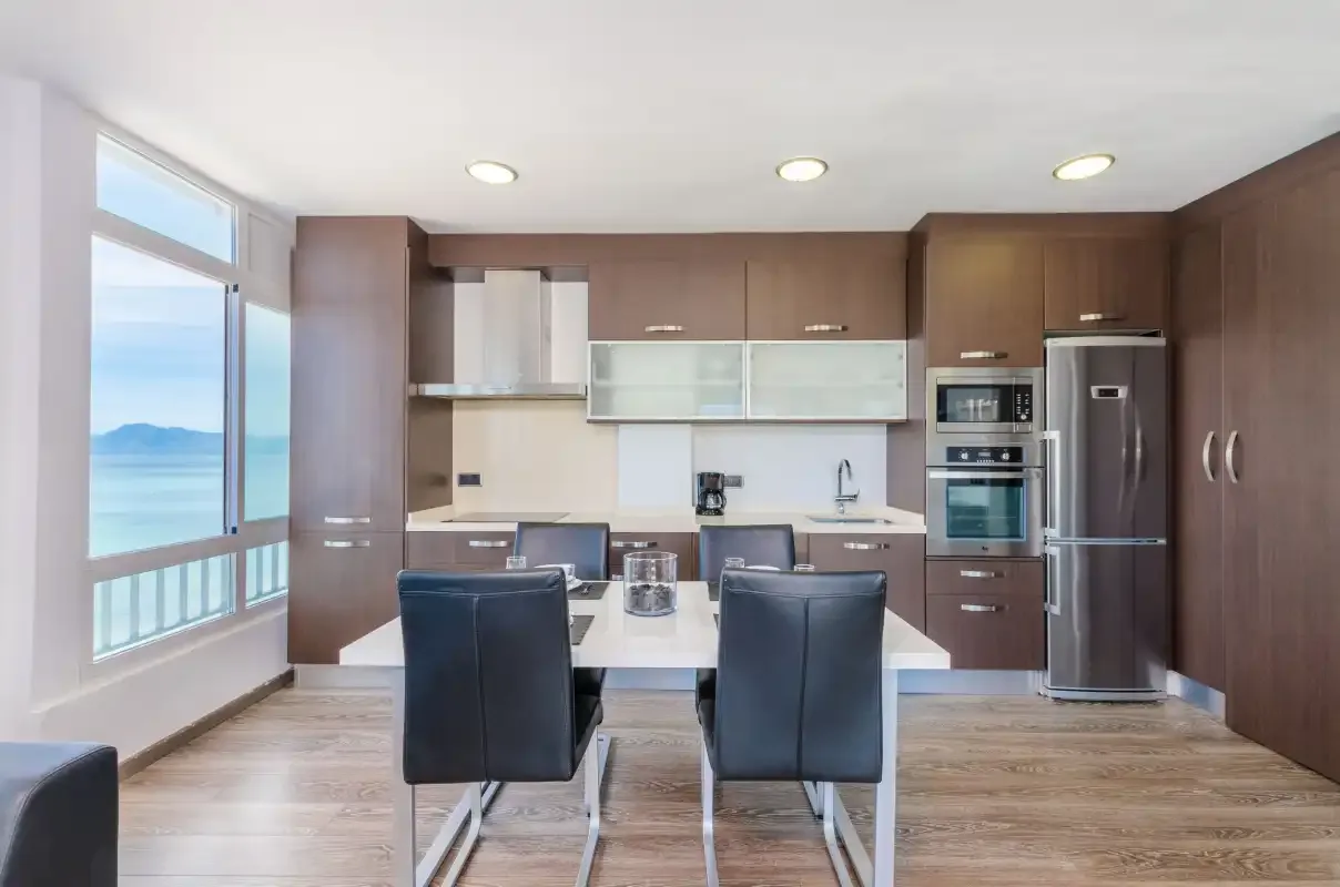Una cocina moderna con zona de comedor, armarios oscuros y un ventanal.