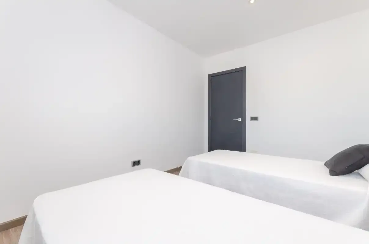 Un dormitorio luminoso con dos camas y una puerta oscura.