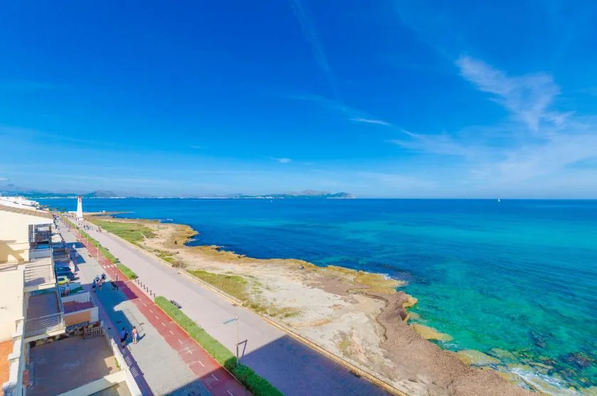 Un paseo marítimo bordea una costa rocosa junto a aguas azules y transparentes.