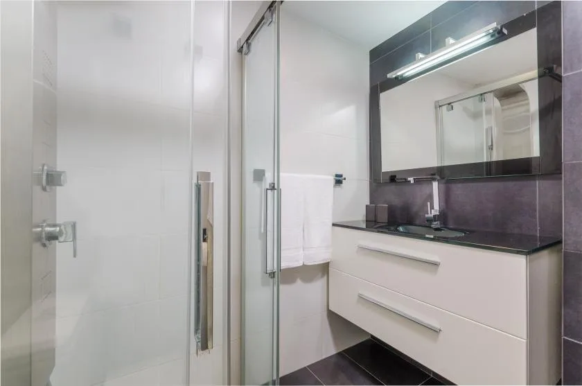Un baño moderno con una ducha de vidrio y un lavabo suspendido.
