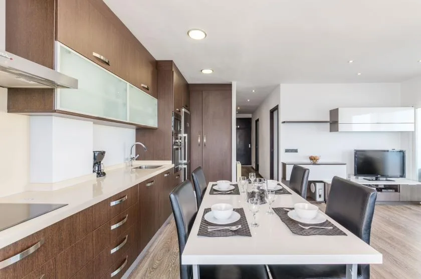 Una cocina moderna y comedor con una mesa larga puesta junto a la encimera.