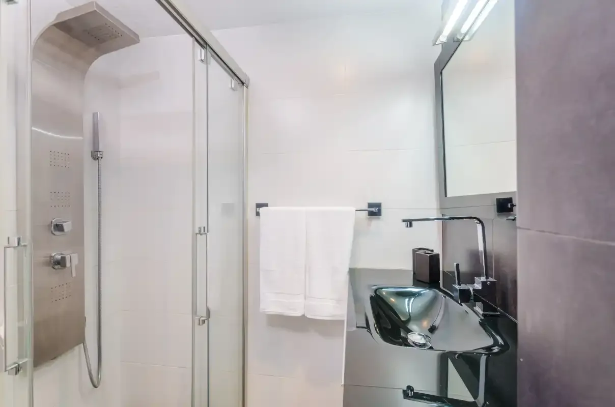 Un baño moderno con una ducha de cristal y un lavabo.
