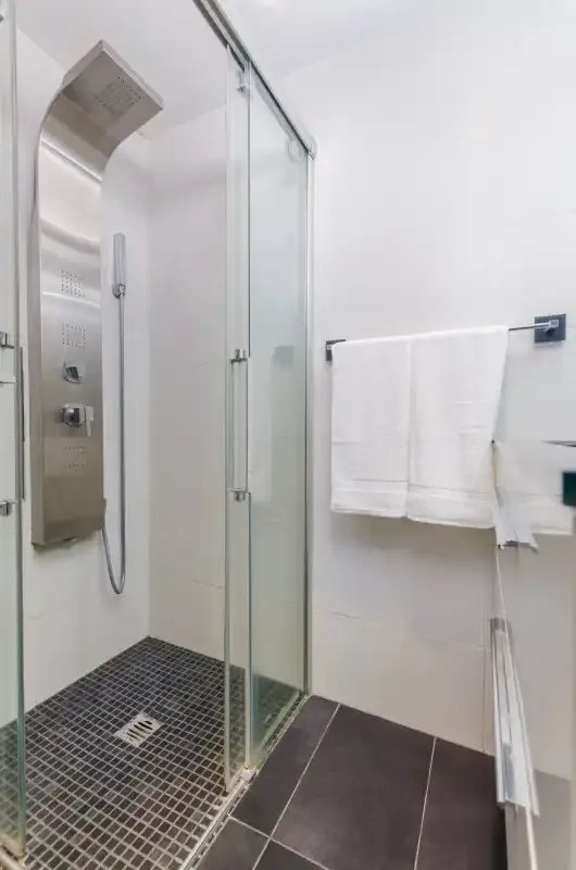 Un baño moderno con una ducha de cristal y toallas blancas.