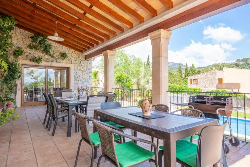 A covered outdoor dining terrace with tables, seating, and views of greenery.