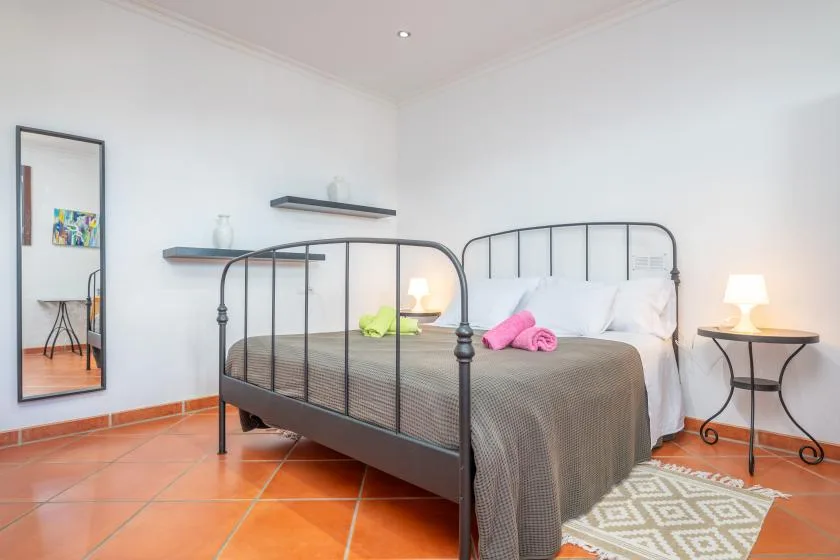 A bedroom with a metal bed, bedside tables, and white walls.