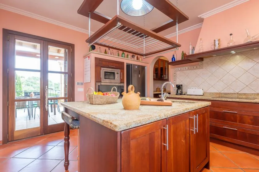 A spacious kitchen with a central island and glass doors opening to a patio.