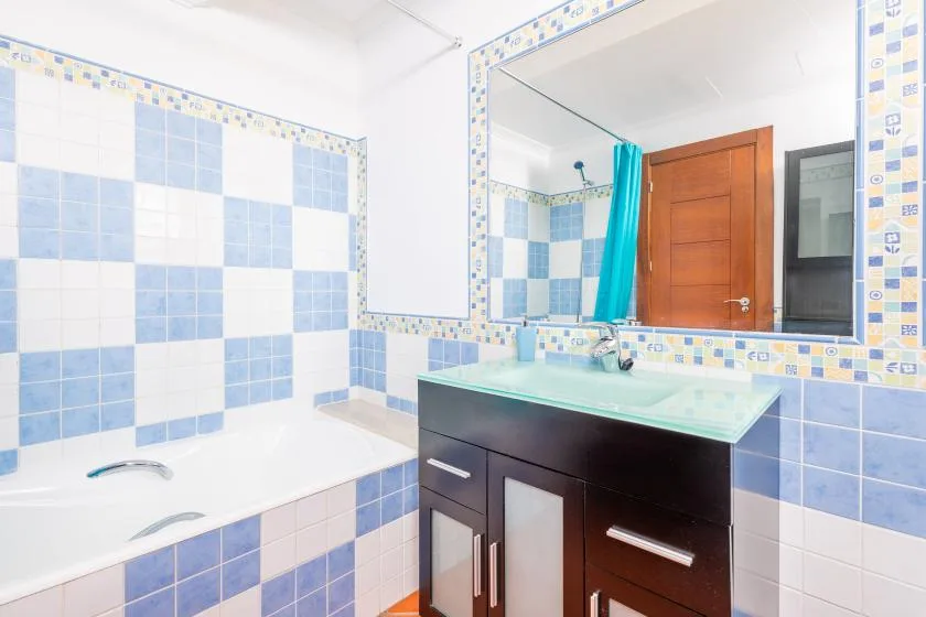A tiled bathroom with a bathtub, vanity, and large wall mirror.