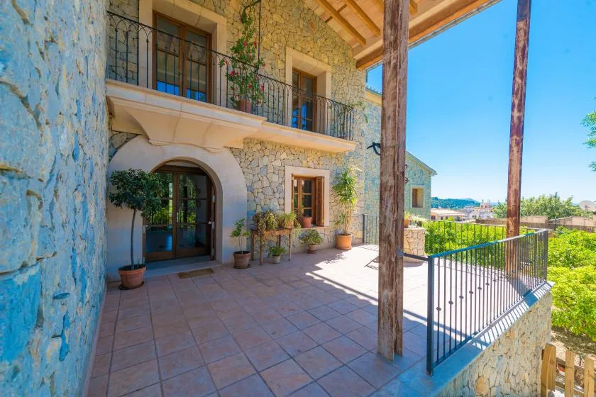 A stone house patio with potted plants and a railing overlooking the landscape.