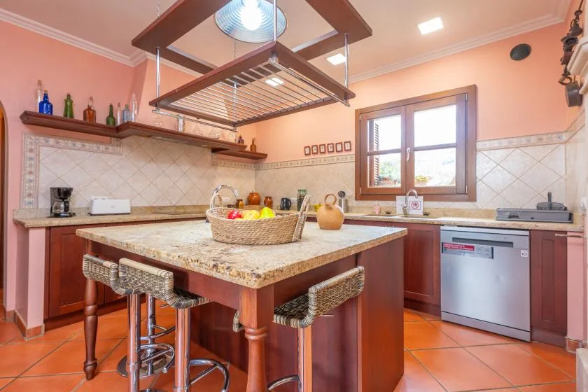 A warm-toned kitchen with a central island and a window above the sink.